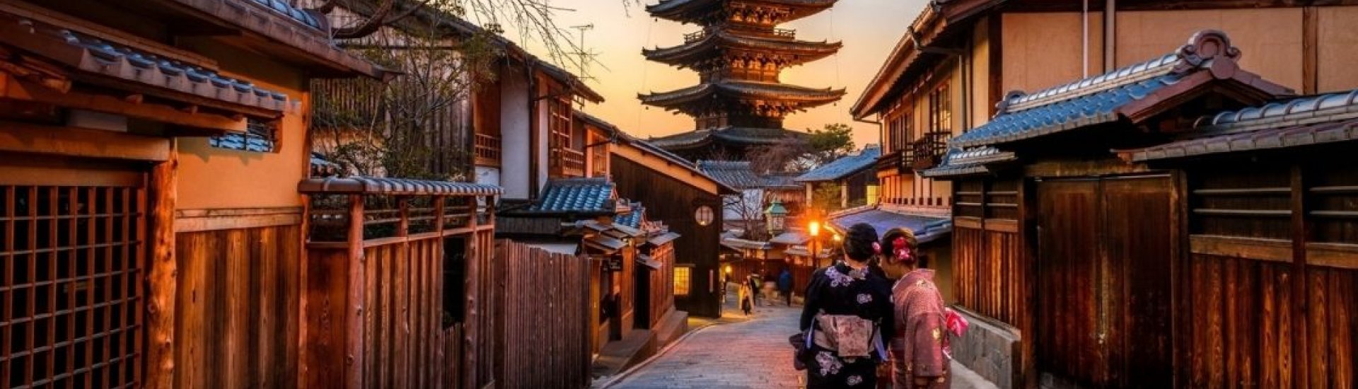 two geishas walking through kyoto gion district at sunset